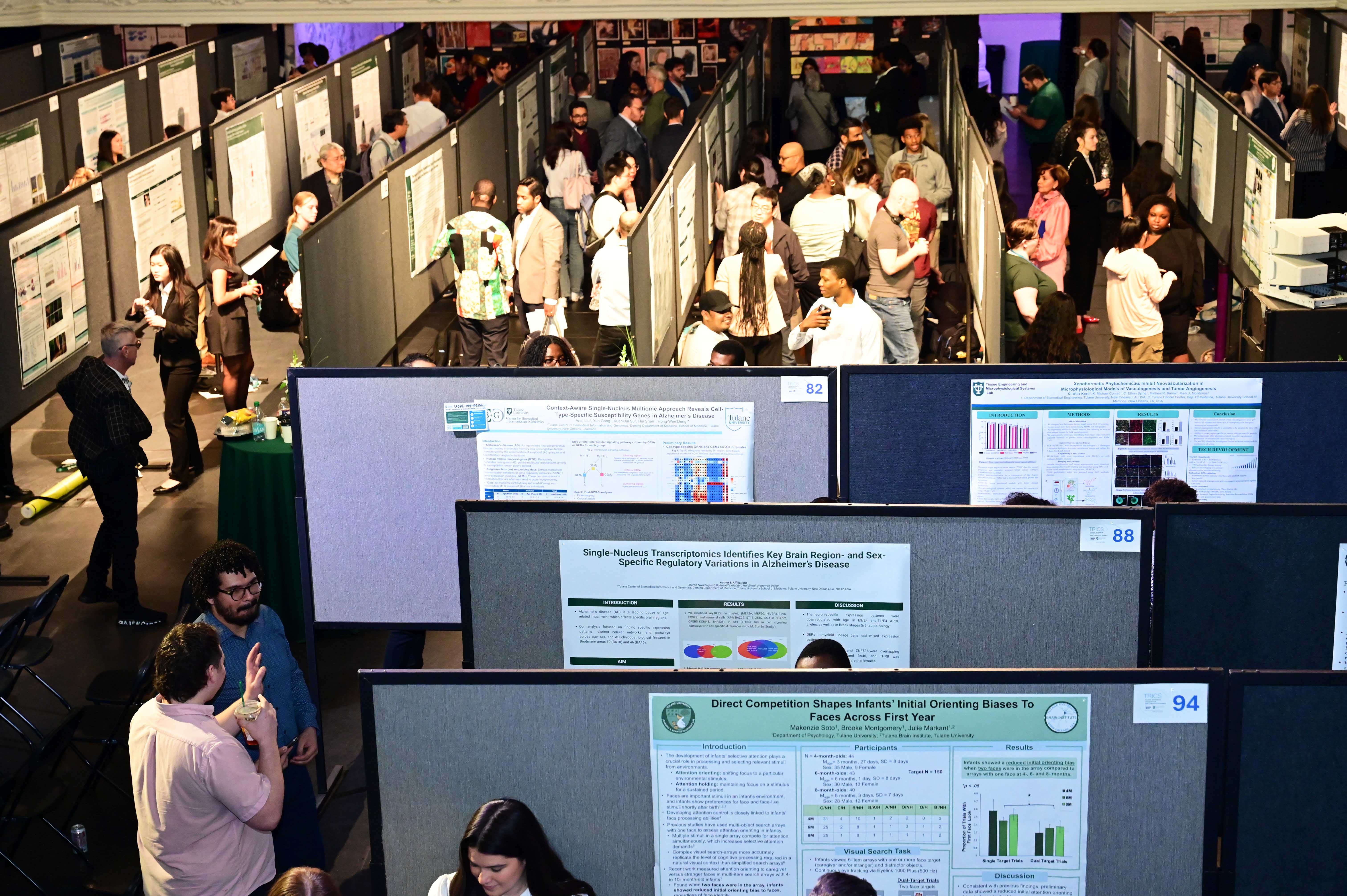 Crowded conference hall with people viewing scientific posters and networking.