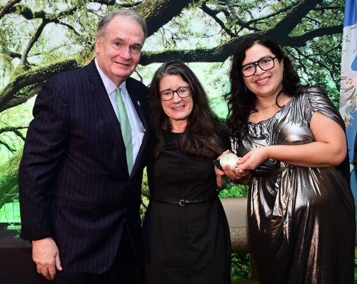 Smiling man with two women, one presenting the Research Hall of Fame medal.